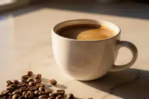 tasse de café filtré en céramique blanche sur comptoir de pierre claire, lumière du matin et grains de café