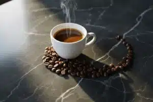 Tasse d'espresso en porcelaine blanche sur marbre gris avec grains de café, illustrant la caféine du café
