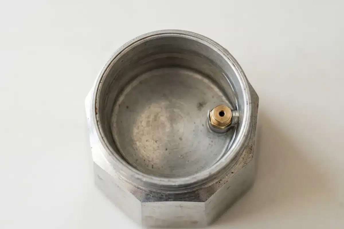 Niveau d'eau dans le réservoir d'une cafetière italienne Vue de dessus du réservoir inférieur d'une cafetière italienne, valve de sécurité dorée visible sur le côté