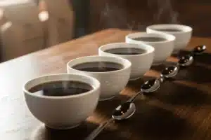 Dégustation du café : rangée de bols de cupping fumants avec leurs cuillères