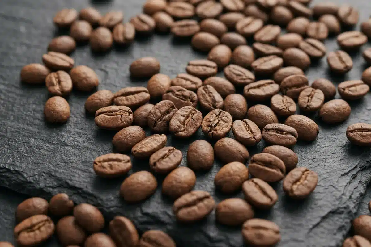 Grains de café à torréfaction légère Grains de café arabica torréfiés couleur brun chaud, dispersés sur une ardoise sombre