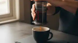 préparation d'un café Aeropress, mains pressant le piston au-dessus d'une tasse en céramique