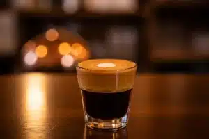 Cortado dans un petit verre transparent, espresso brun et lait chaud, comptoir de café artisanal
