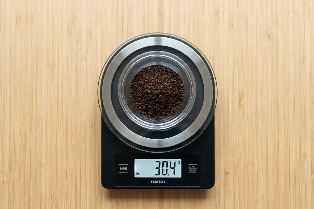 Dosage café filtre sur balance numérique Balance numérique vue de dessus avec bol de café moulu dosé, surface bambou
