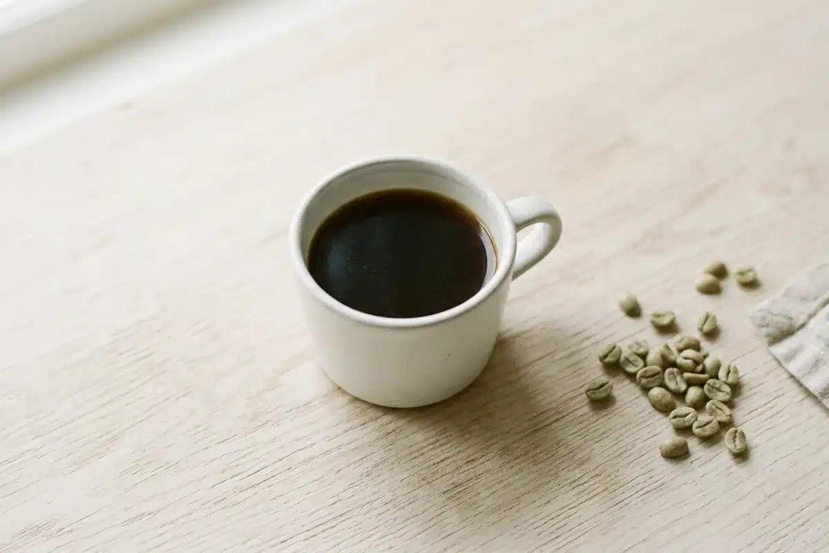 Tasse de café décaféiné blanc posée près de grains de café verts, alternative pour personnes anxieuses