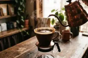 Préparation d'un café filtre en pour-over : bouilloire à col de cygne en cuivre versant l'eau sur le filtre